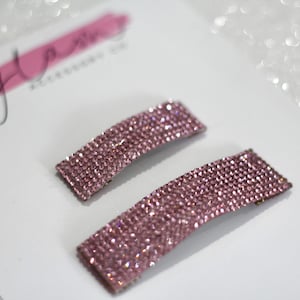 May include: Two pink rhinestone hair clips. The clips are rectangular and covered in small pink rhinestones.