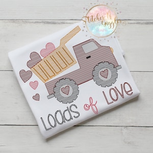 May include: A white t-shirt with a red dump truck carrying pink hearts. The truck has gray tires and a brown bed. The text "Loads of Love" is embroidered in gray below the truck.