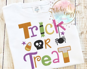 May include: White children's t-shirt with the words "Trick or Treat" embroidered in colorful letters. The letters are decorated with candy corn, a skull, a spider, and a candy cane.