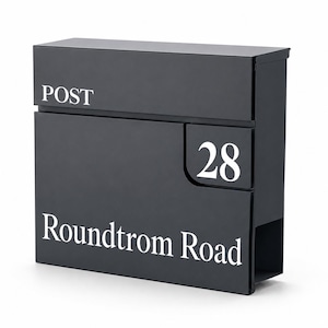May include: A rectangular matte black metal post box featuring the word POST in white lettering at the top left, the number 28 in white on the right side, and the text Roundtrom Road in white lettering across the bottom section of the front panel.