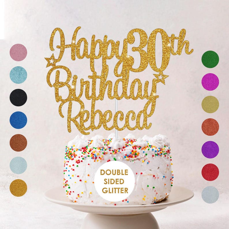A white birthday cake with colorful sprinkles and a gold glitter topper that says "Happy 30th Birthday Rebecca" in a decorative font.