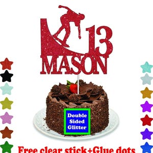 A chocolate cake with a red glittery topper that says "MASON" and a red skateboard silhouette. The cake is placed on a white plate, and there are colorful star-shaped decorations surrounding it.