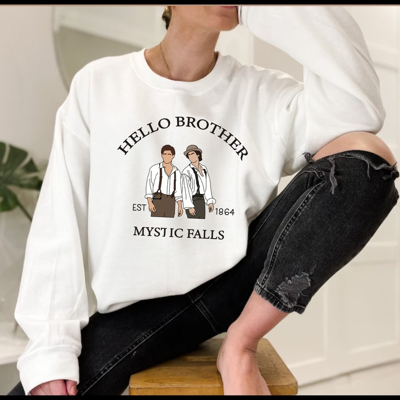 May include: White sweatshirt with a graphic print of two men in suspenders and the text "Hello Brother Est 1864 Mystic Falls".