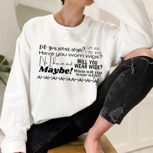May include: White sweatshirt with black text that reads "Do you wear wigs? Uh no. Have you worn wigs? No I have not. Will you wear wigs? Maybe! When will you wear wigs? AHAHAHAHAHAHA!!"
