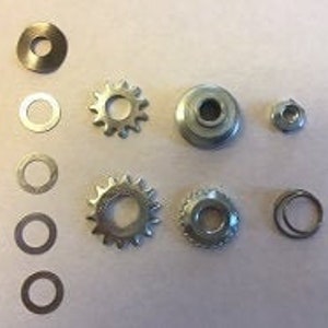 May include: A set of silver-toned metal gears and washers. The set includes two large gears, two small gears, and four washers.