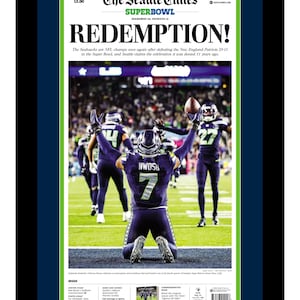 May include: A framed newspaper front page from The Seattle Times, featuring the headline "REDEMPTION!" and a photo of Seattle Seahawks players celebrating a Super Bowl victory. The date is Monday, February 9, 2020.