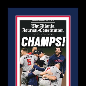 May include: A newspaper front page with a photo of baseball players celebrating. The headline reads "CHAMPS!" and the subheadline reads "BRAVES OVERCOME OBSTACLES, DEFY LOGIC - AND WIN WORLD SERIES".