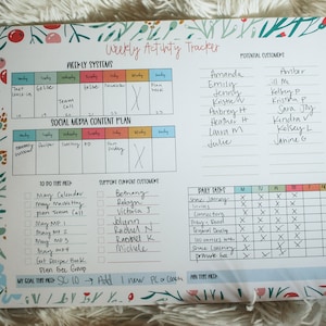 May include: A weekly activity tracker planner with a floral design. The planner includes sections for weekly systems, social media content plan, to do this week, support current customers, daily tasks, and a weekly grid. The planner also includes a list of potential customers.