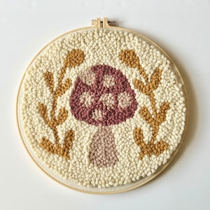 Extra large 12 inch embroidery hoop featuring a dark pink mushroom with beige spots, surrounded by yellow laurel leaves and white background