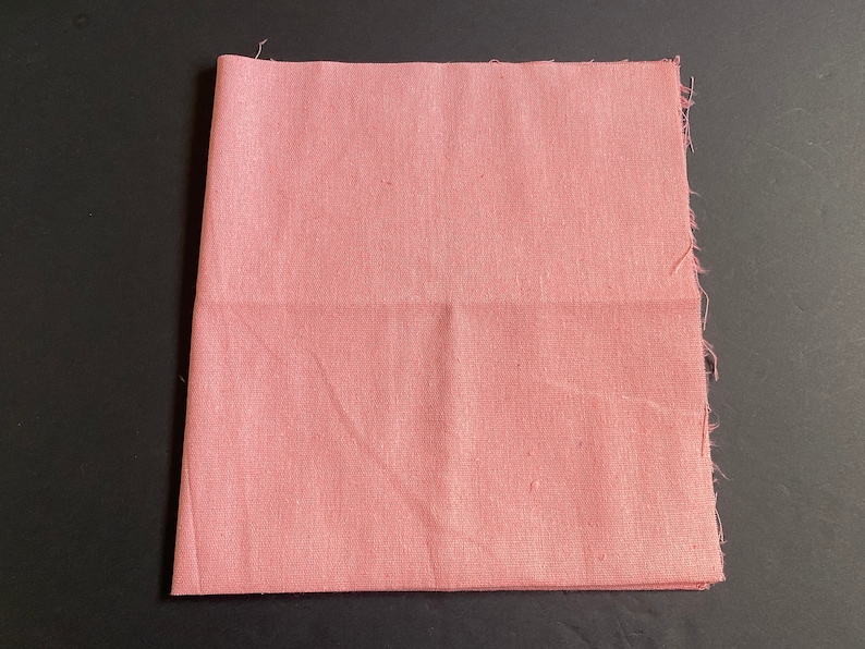 1 piece of 20 inch by 20 inch cotton linen fabric in pink color. It is folded in half and has raw edges.