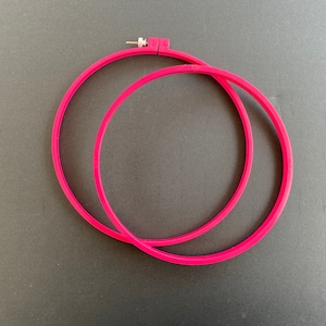 May include: Two bright pink embroidery hoops, one slightly overlapping the other. The top hoop has a metal screw and a plastic piece with the text "20 CM" and "TOP". The hoops are approximately 8 inches in diameter.