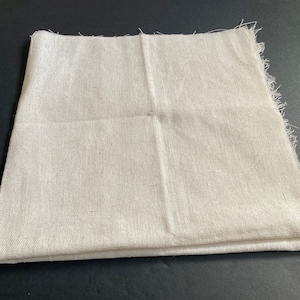 1 piece of 20 inch by 20 inch cotton linen fabric in off white. It is folded in half and has raw edges.