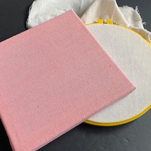 1 wood frame with pink linen cotton fabric stretched over it and 1 8 inch embroidery hoop with off white cotton linen punch needle fabric stretched over it.