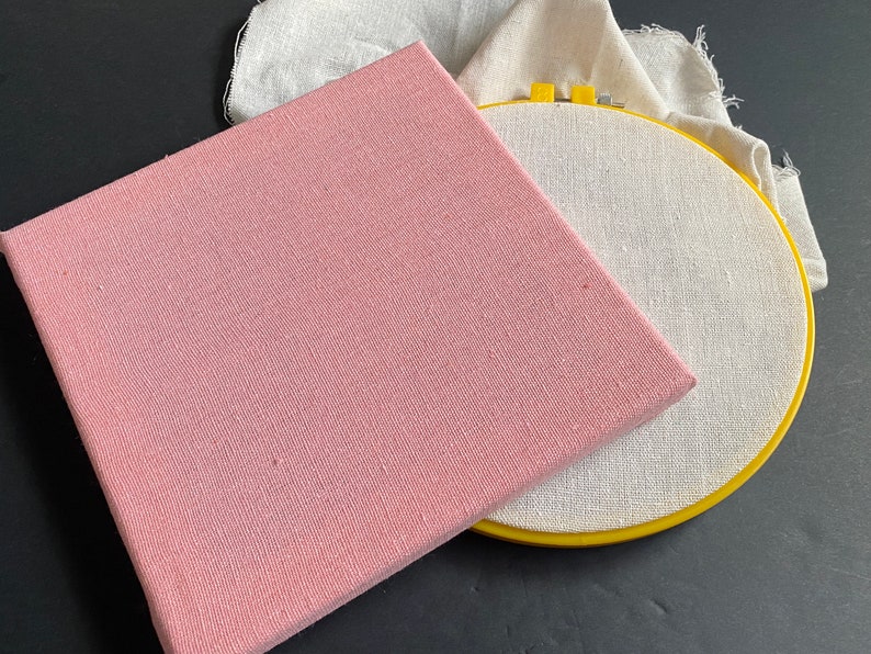 1 wood frame with pink linen cotton fabric stretched over it and 1 8 inch embroidery hoop with off white cotton linen punch needle fabric stretched over it.