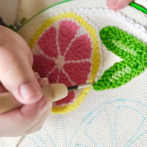 Hand using punch needle on the fabric to make the lemon slices