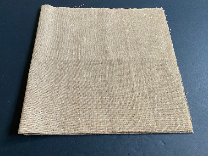 1 piece of 20 inch by 20 inch cotton linen fabric in khaki brown color. It is folded in half and has raw edges.