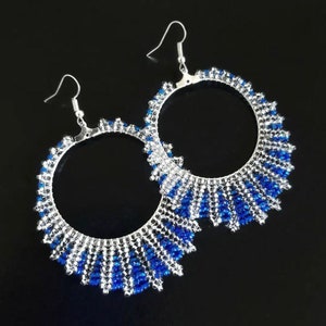 May include: A pair of large hoop earrings made with silver and blue beads. The earrings have a graduated design with the blue beads getting larger towards the bottom.