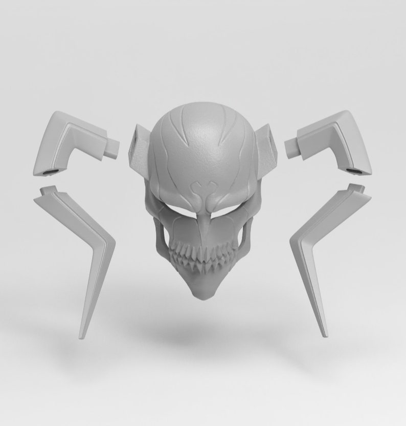 May include: A gray, skull-shaped mask with detached angular pieces. The mask features a detailed skull design with visible teeth and eye sockets. The detached pieces are geometric and angular, suggesting a modular or assembled design. The mask is likely for cosplay or costume use.