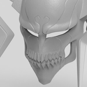 May include: A gray, detailed mask with a skeletal design, featuring sharp teeth and a prominent jawline. The mask has a textured surface and is likely a cosplay or decorative item.