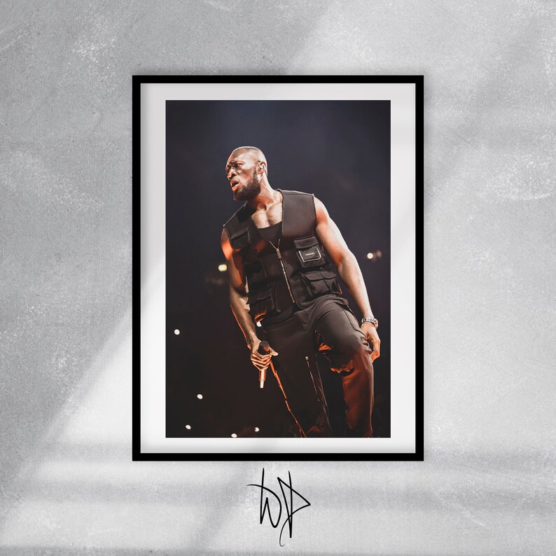 May include: A black and white photo of a man wearing a black vest and black pants, performing on stage with a microphone in his hand.