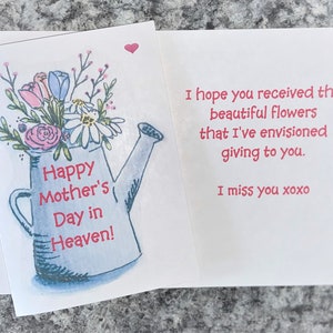 May include: A blue watering can with a bouquet of pink, white, and blue flowers. The text "Happy Mother's Day in Heaven!" is written on the can.