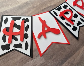 May include: A red and black banner with the word "Happy" in red letters. The banner has a cow print pattern.