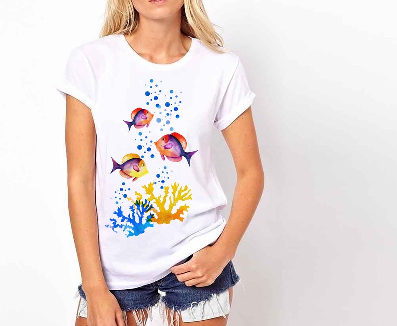 May include: White t-shirt featuring a colourful design of fish swimming through bubbles and coral. The fish are orange, yellow, blue and purple.