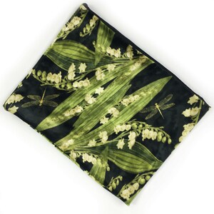 May include: A black velvet zippered pouch with a green and white floral print featuring lily of the valley flowers and dragonflies.