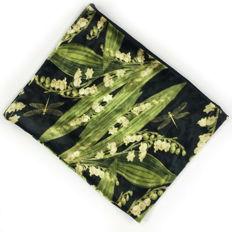 May include: A black velvet zippered pouch with a green and white floral print featuring lily of the valley flowers and dragonflies.