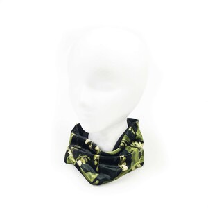 May include: A black velvet neck warmer with a green floral pattern. The neck warmer is folded and displayed on a white mannequin head.