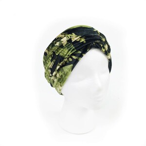 May include: A black and green floral print turban headband. The headband is made of a soft, velvet fabric and is designed to be worn as a stylish accessory.