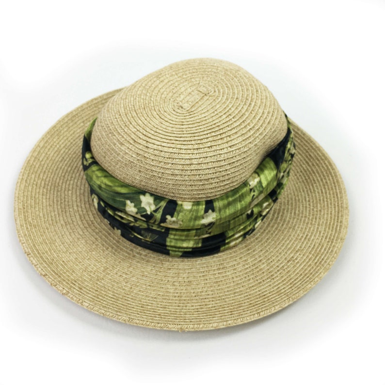 May include: A straw hat with a wide brim and a green and black floral patterned band.