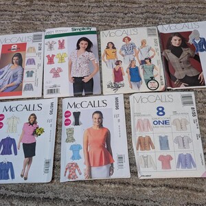 May include: A collection of sewing pattern envelopes featuring various designs for tops, jackets, and dresses. The patterns include images of the finished garments and are from brands like McCall's and Simplicity.