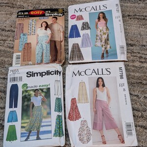 May include: Four vintage sewing pattern envelopes featuring designs for pants and skirts. The patterns are from Simplicity and McCall's, with images of the finished garments on the front. The envelopes are on a neutral-colored carpet.
