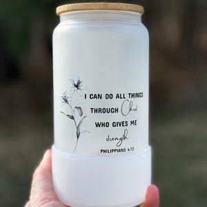 Puede incluir: Botella de agua de vidrio blanco esmerilado con tapa de bambú. La botella tiene un diseño floral en blanco y negro y el texto "Puedo hacer todas las cosas por medio de Cristo que me fortalece Filipenses 4:13".