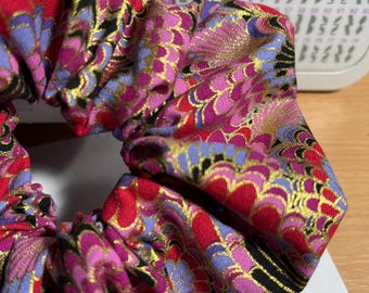 Coletero artesanal de algodón estilo kimono japonés con estampado en tonos rosas, rojos, lavanda, negro y detalles dorados, con pompón.
