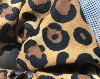 May include: A brown and black leopard print scrunchie hair tie.