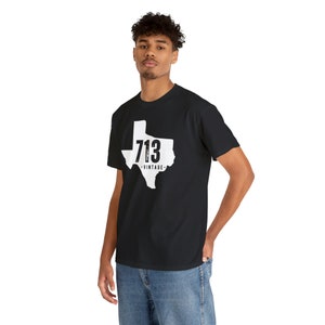 May include: Black t-shirt featuring a white outline of the state of Texas with the number "713" and the word "VINTAGE" printed on it. The shirt is made of a soft, comfortable material.