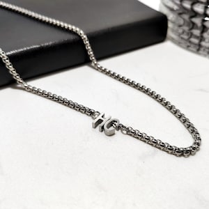 May include: A silver chain necklace with a small pendant that says "HC".