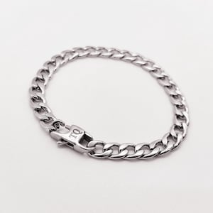 May include: A silver chain bracelet with a clasp that has the letters "TQ" engraved on it.
