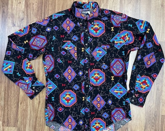 May include: A long-sleeved button-down shirt with a black background and a colorful geometric pattern. The shirt has a pointed collar and a single button closure at the top.