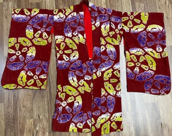 May include: A red kimono with a purple and yellow floral pattern. The kimono has long sleeves and a wide collar.