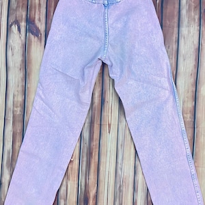 Pu&ograve; includere: Jeans in denim lilla chiaro con vita alta e classico design a cinque tasche. I jeans hanno un aspetto sbiadito, lavato con acidi e un taglio dritto. La vista posteriore mostra i passanti per la cintura e l'etichetta del marchio.
