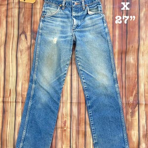 May include: Vintage blue denim jeans with a faded wash. The jeans are straight-legged and have a classic five-pocket design. The tag reads "The Packard Vintage". The jeans measure 25" x 27".