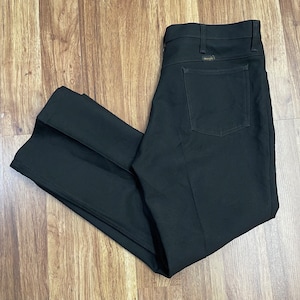 Puede incluir: Un pantalón negro de pierna recta con un bolsillo trasero que tiene el logotipo de Wrangler.
