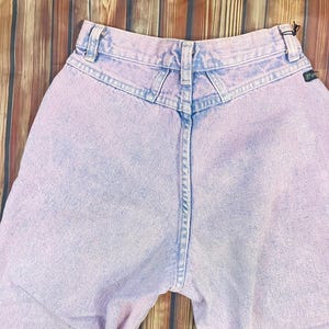 Pu&ograve; includere: Jeans vintage a vita alta in un lavaggio acido lilla chiaro. I jeans presentano un classico design a cinque tasche, passanti per cintura e un carr&egrave; a forma di V sul retro. Il denim ha un aspetto sbiadito e usurato, con una piccola etichetta nera sul retro.