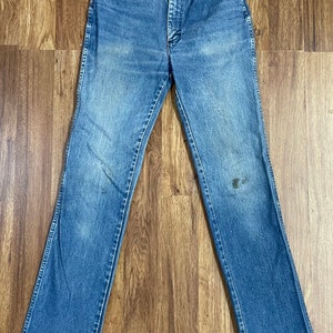 May include: A pair of blue denim jeans with a straight leg fit. The jeans have a button fly and belt loops.