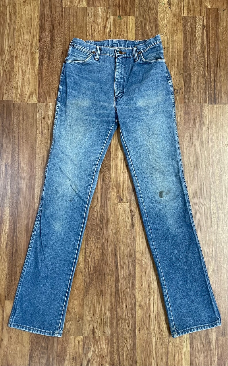 May include: A pair of blue denim jeans with a straight leg fit. The jeans have a button fly and belt loops.