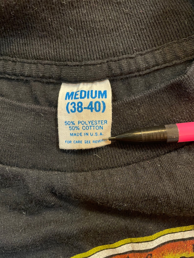 Puede incluir: Una etiqueta de ropa azul y blanca con el texto "MEDIUM (38-40)" y "50% POLI&Eacute;STER 50% ALGOD&Oacute;N HECHO EN EE. UU. PARA EL CUIDADO VER EL REVERSO"
