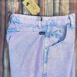 Pu&ograve; includere: Jeans Wrangler vintage lilla chiaro con lavaggio sbiadito. I jeans hanno un classico design a cinque tasche e una toppa con il logo Wrangler. &Egrave; attaccata un'etichetta Blackbird Vintage.